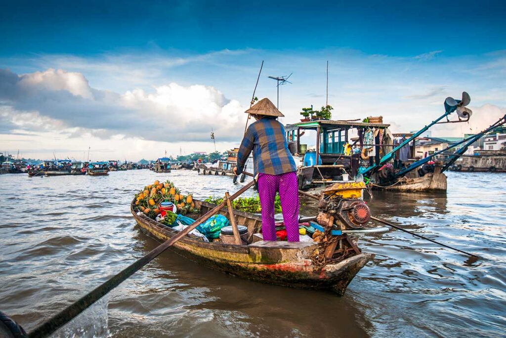 Frau rudert mit ihrem Boot über den schwimmenden Markt von Cai Rang in Can Tho im Mekong-Delta