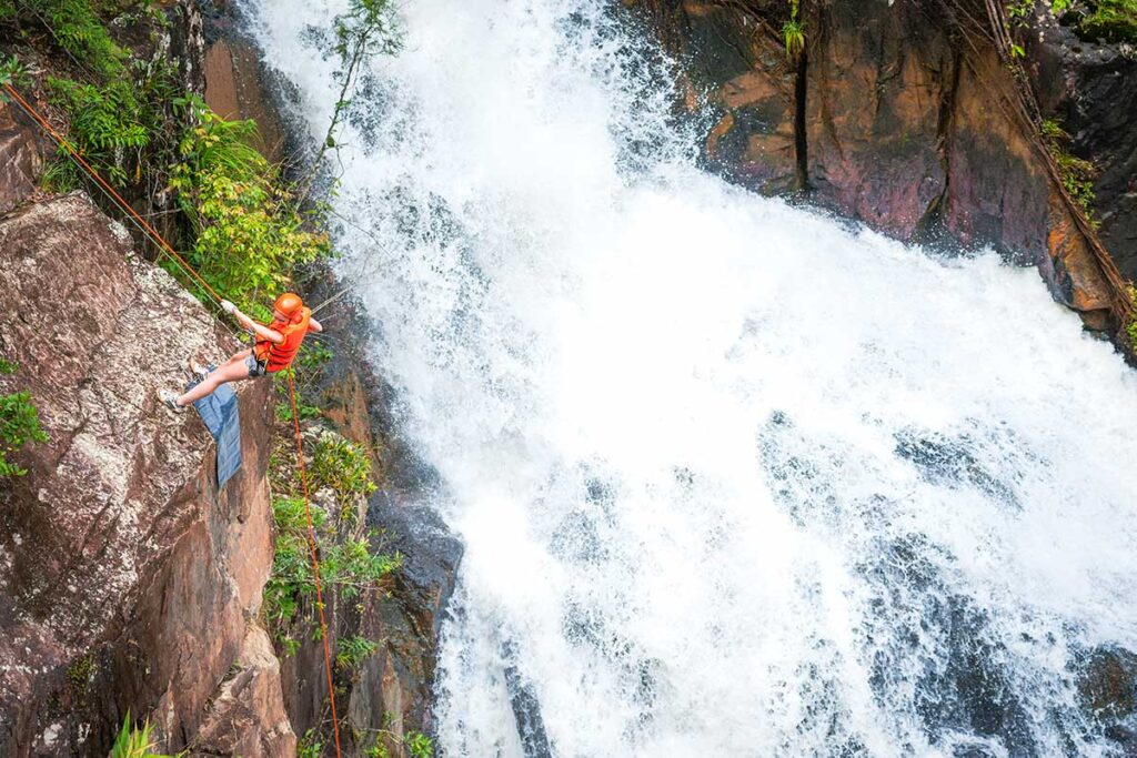 Ein Mann seilt sich beim Canyoning in Dalat neben einem Wasserfall ab