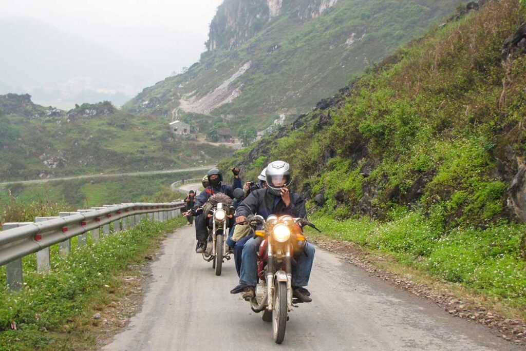 Easy Riders fahren mit Touristen auf dem Rücken ihres Motorrads den Ha Giang Loop entlang