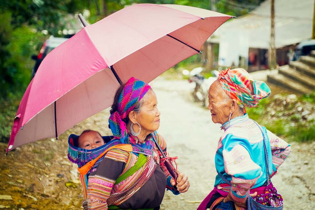 Zwei ethnische Minderheiten in Vietnam mit Regenschirm, der vor dem Wetter schützt