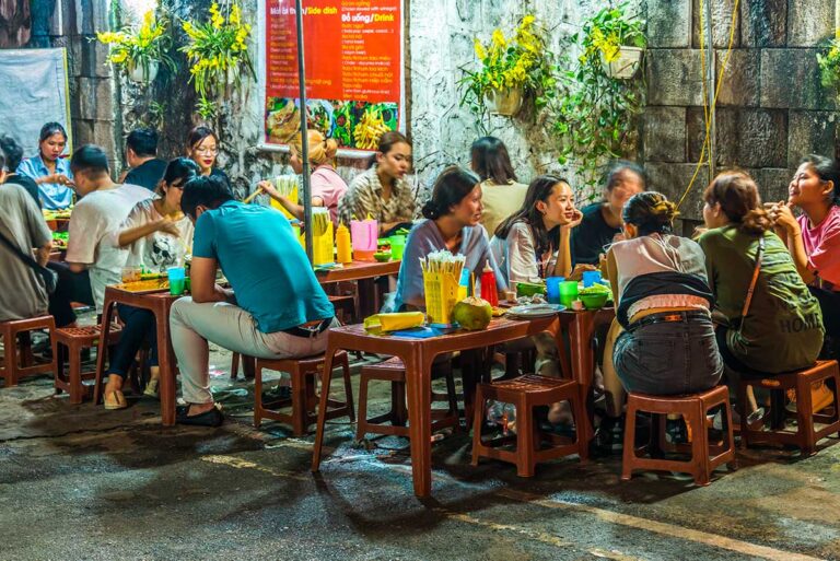Streetfood in Hanoi – Menschen sitzen auf niedrigen Hockern und essen lokales Streetfood