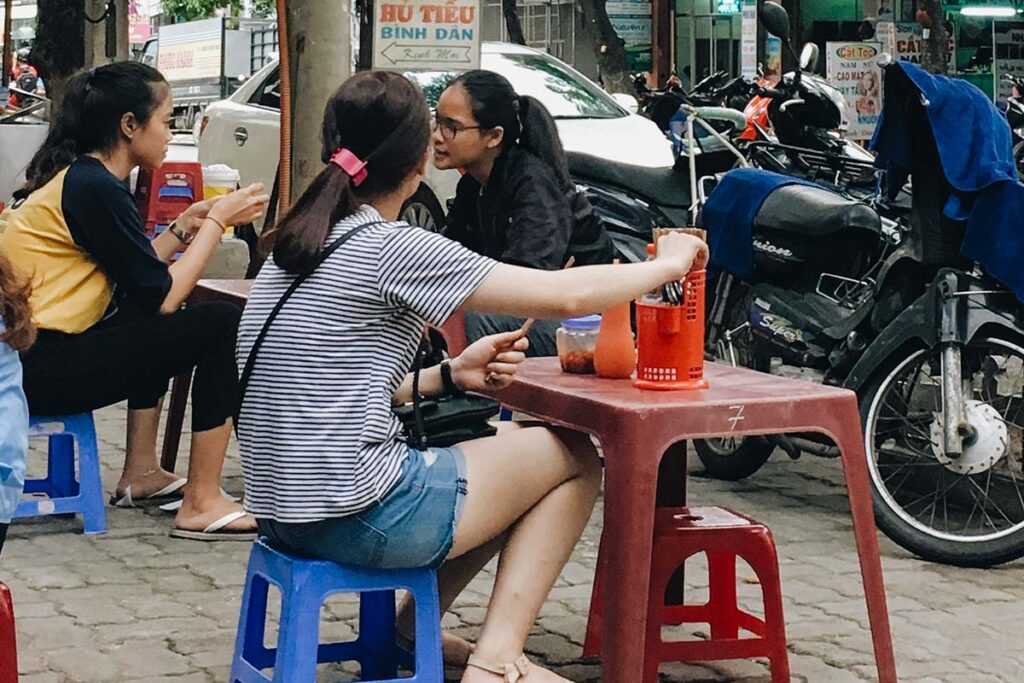Menschen genießen Street Food auf dem Gehweg in Vietnam.