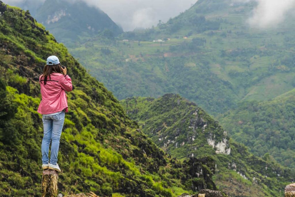 Frau macht während einer Wanderung ein Foto der Berglandschaft von Ha Giang