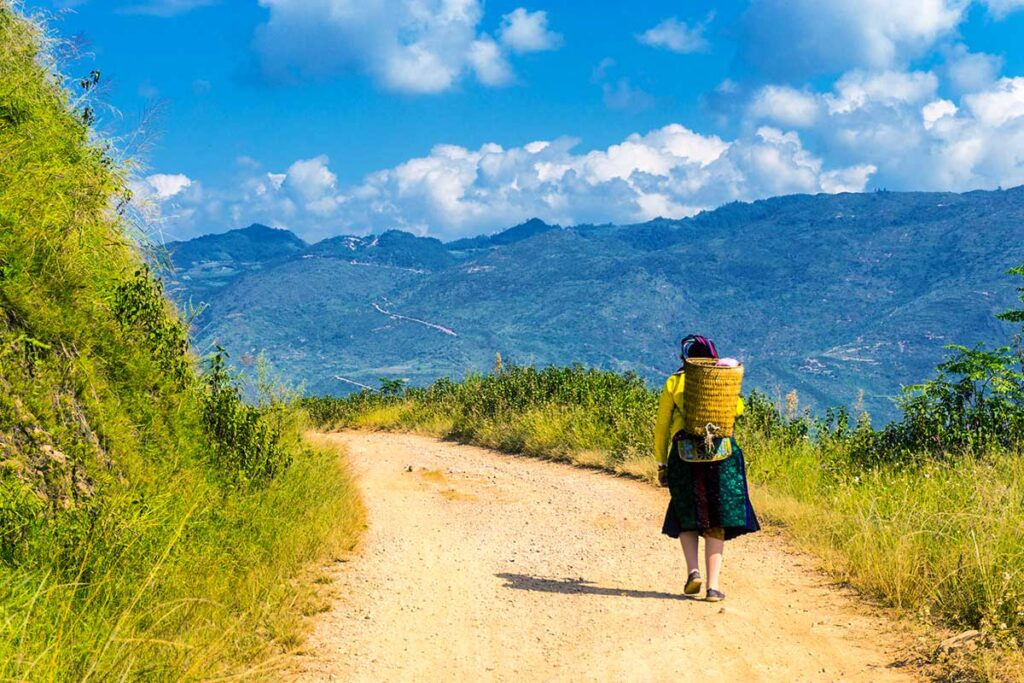 Eine ethnische Frau geht eine verlassene Straße in Ha Giang entlang