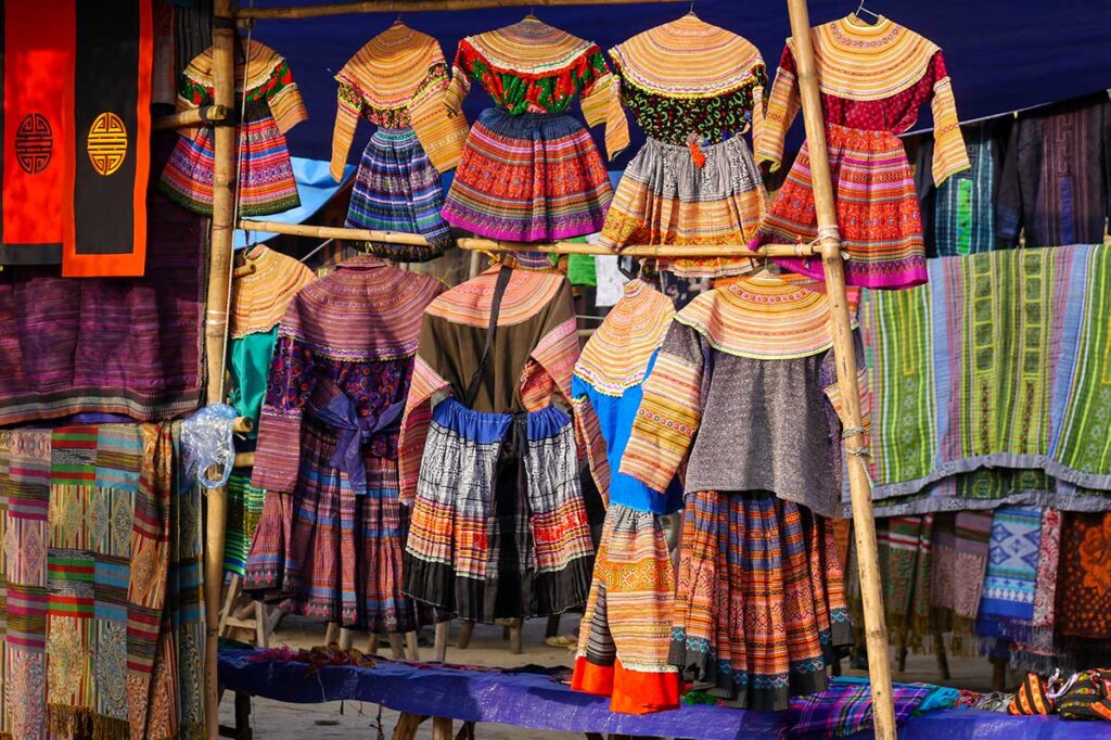 Ethnische traditionelle Kleidung, die an einem Stand auf dem Bac Ha-Markt hängt