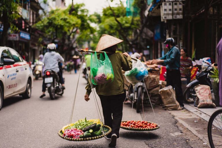 Ein Einheimischer trägt Waren auf seiner Schulter in der Altstadt von Hanoi