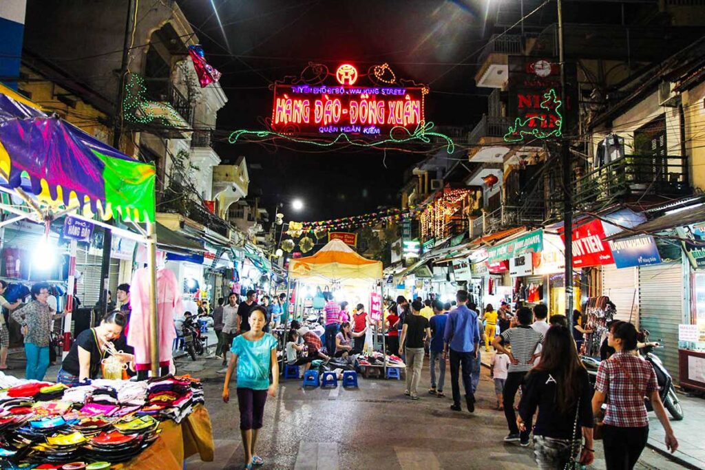 Menschen, die an Ständen auf dem Nachtmarkt in Hanoi Waren verkaufen (nur am Wochenende)
