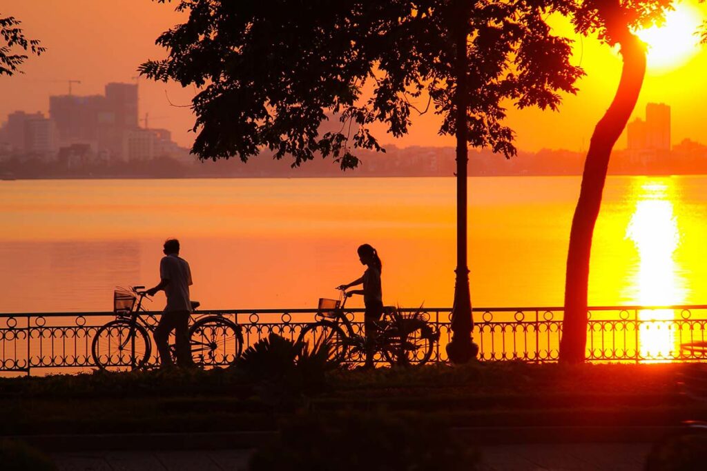 2 Personen mit Fahrrad während des Sonnenuntergangs am Westsee in Hanoi