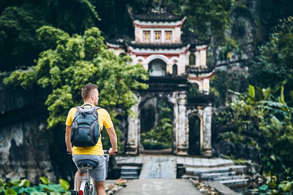 A tourist on a cycle infront of the Bich Dong Pagoda in Ninh Binh