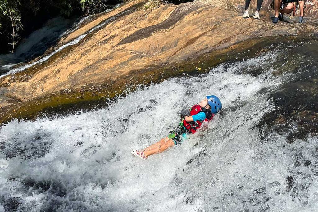 Ein Mädchen rutscht beim Canyoning in Dalat eine natürliche Rutsche mit Stromschnellen hinunter