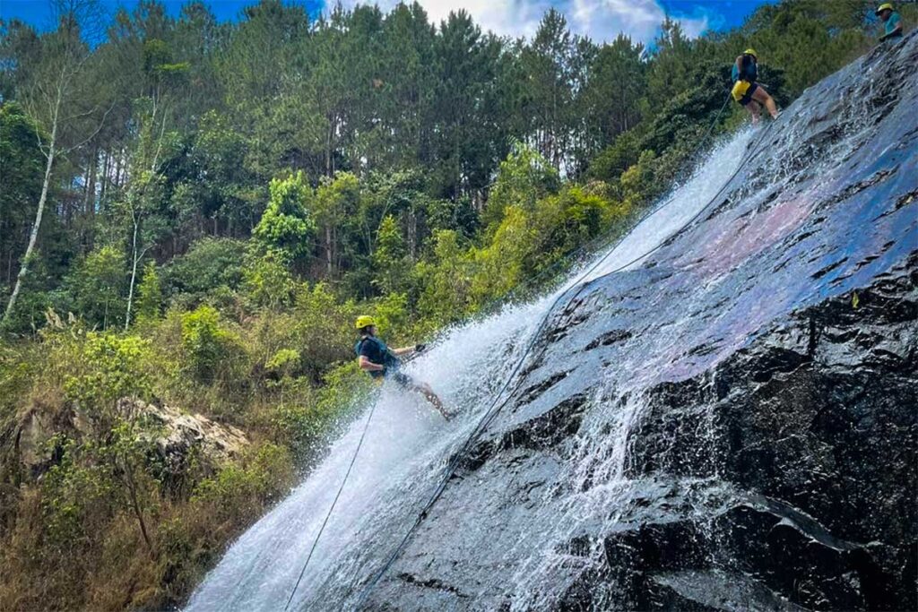 Zwei Personen seilen sich beim Canyoning in Dalat durch einen Wasserfall ab