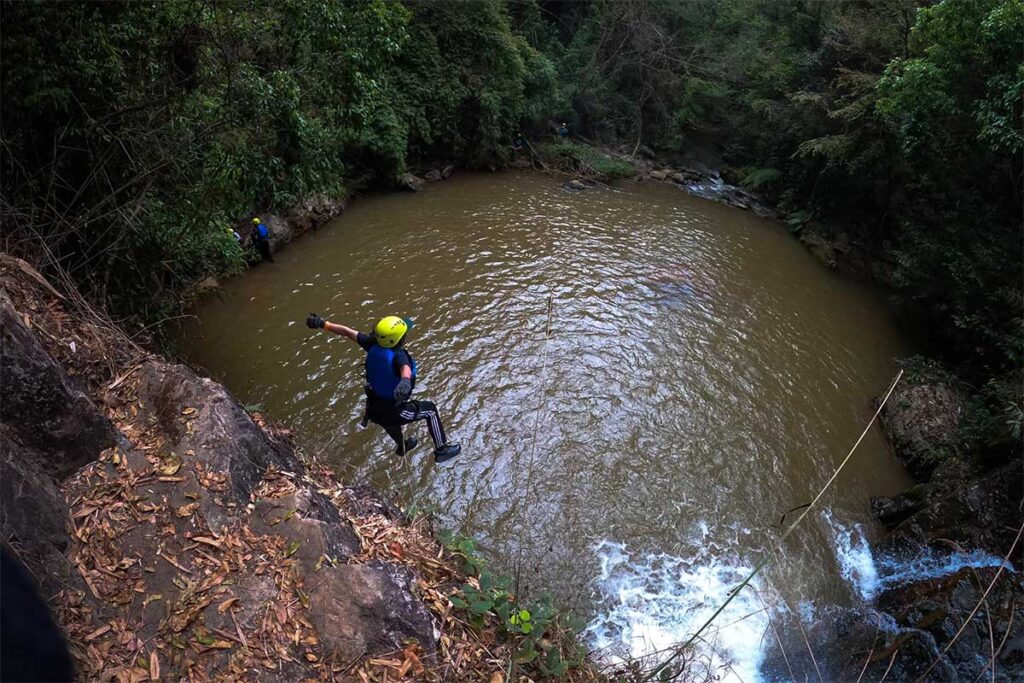 Eine Person springt beim Canyoning in Dalat von einer Klippe