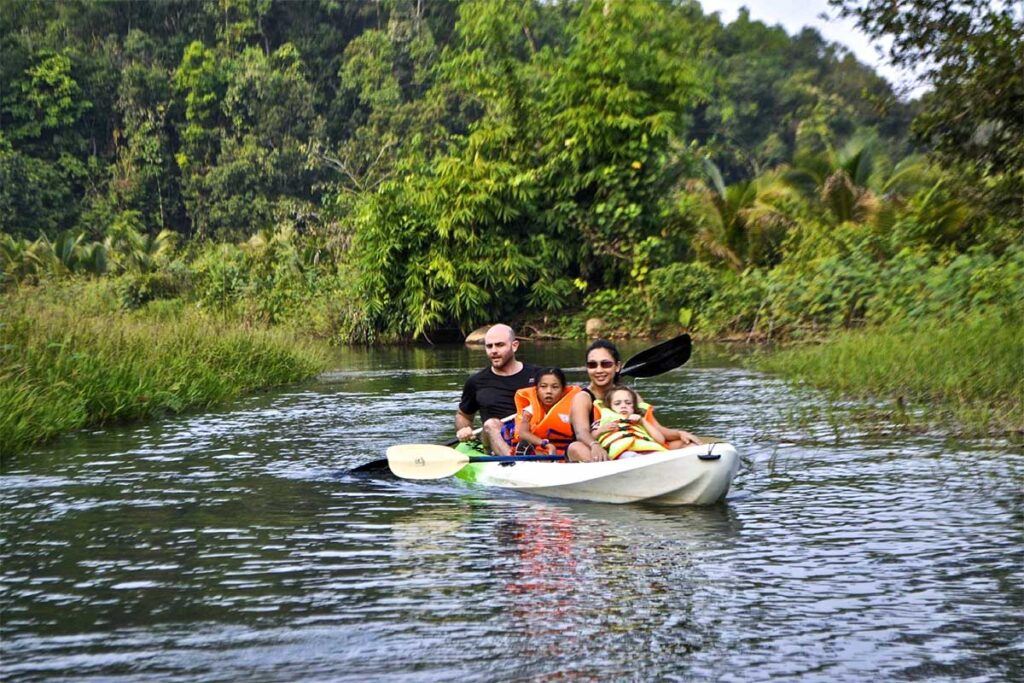 Eine Familie bestehend aus Mutter, Vater und zwei Kindern fährt Kajak auf einem kleinen Fluss im Cat Tien Nationalpark.