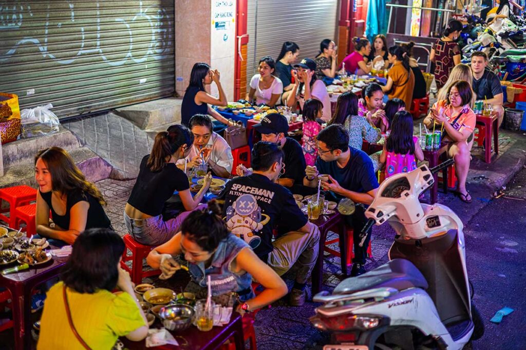 Streetfood in Ho-Chi-Minh-Stadt – Einheimische sitzen auf einem Plastikhocker auf der Straße und essen Streetfood