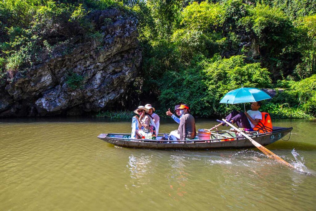 Touristen machen eine Bootstour in Ninh Binh mit einem Ruderboot durch das Gebiet Tam Coc.