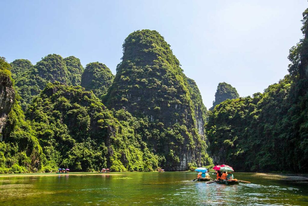 Ruderboote gleiten entlang der atemberaubenden Steilklippen von Trang An in Ninh Binh