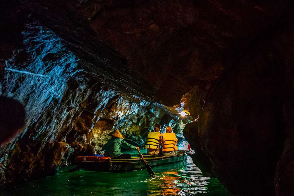 Touristen machen eine Ruderboot-Tour durch eine enge Höhle im UNESCO-Landschaftskomplex Trang An in Ninh Binh