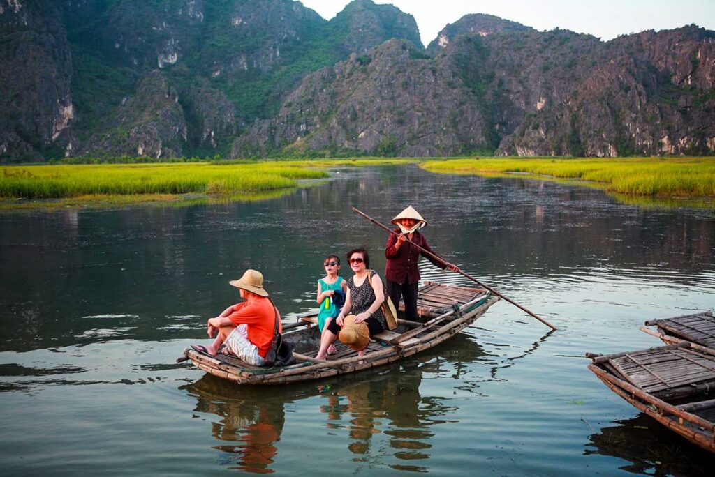 Touristen sitzen auf einem kleinen Boot im Feuchtgebiet des Van Long Naturschutzgebietes in Ninh Binh