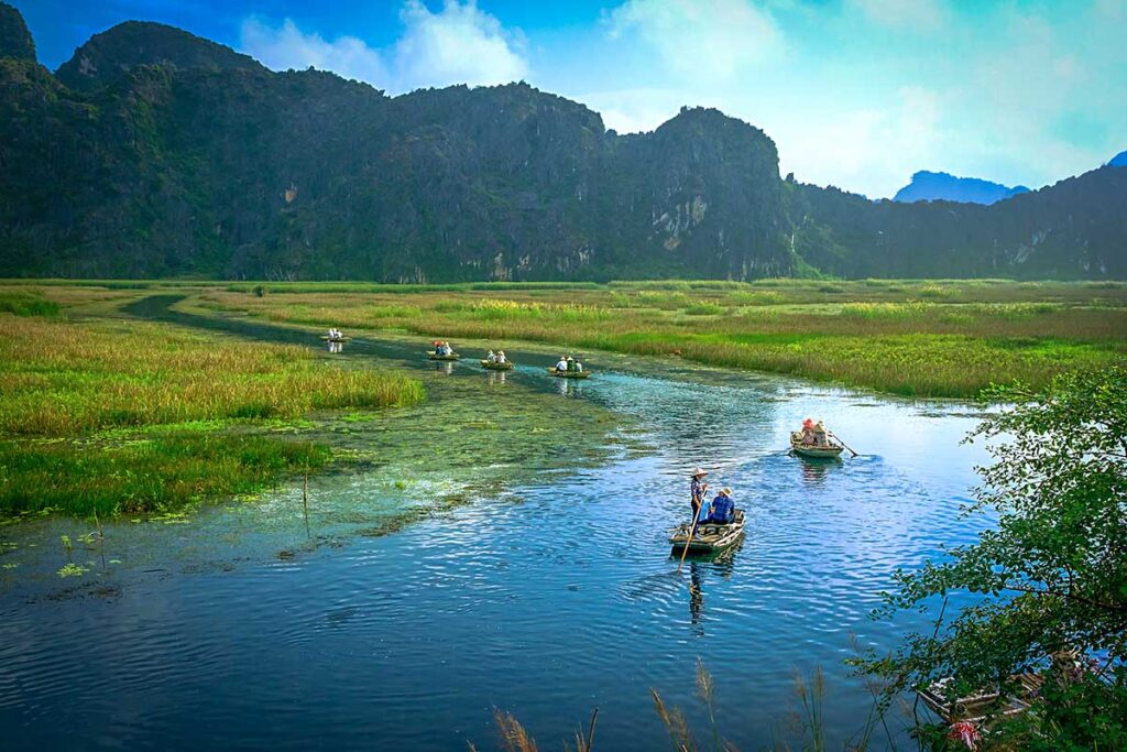 Touristen sitzen auf einem kleinen Boot im Feuchtgebiet des Van Long Naturschutzgebietes in Ninh Binh