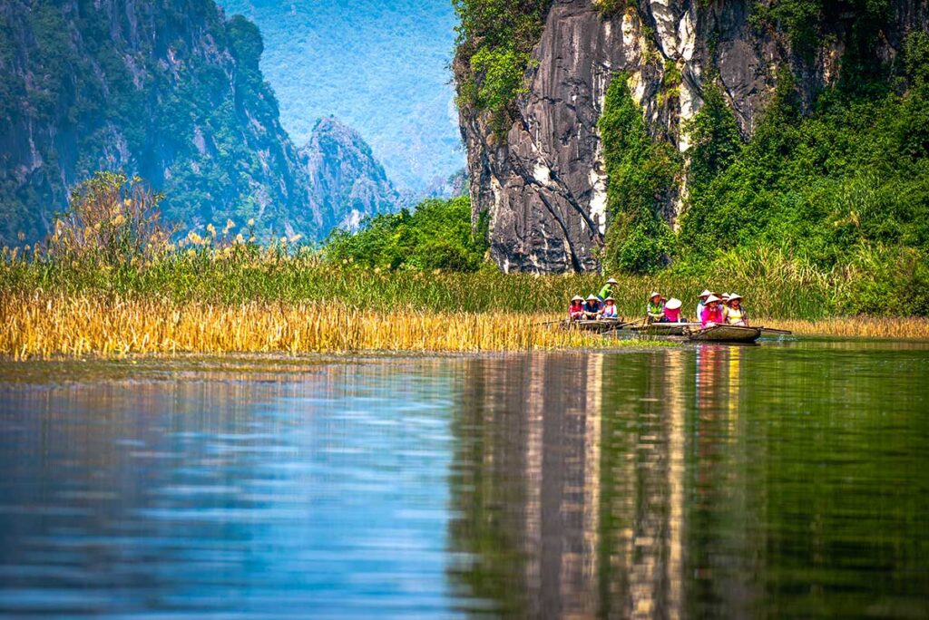 Touristen sitzen auf einem kleinen Boot im Feuchtgebiet des Van Long Naturschutzgebietes in Ninh Binh