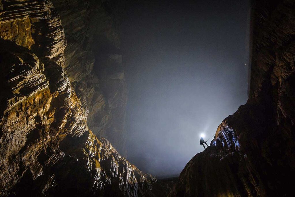 Ein Abenteuerreisender auf einer Höhlenexpedition klettert eine riesige Höhlenwand namens "Die Große Mauer Vietnams" in Hang Son Doong