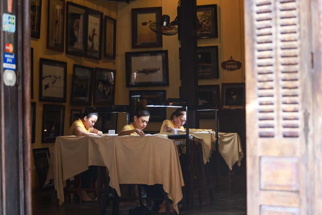 Eine Gruppe von Frauen näht Stoffe, um maßgeschneiderte Kleidung in Hoi An herzustellen.