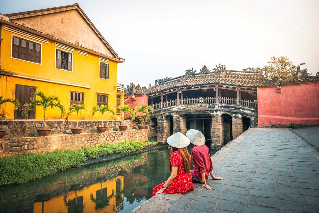 Ein Paar sitzt romantisch neben der berühmten Japanischen Brücke in Hoi An