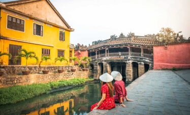 Ein Paar sitzt romantisch neben der berühmten Japanischen Brücke in Hoi An