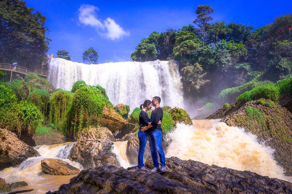 Ein romantisches Paar küsst sich während seiner Flitterwochen in Vietnam vor dem Elefantenwasserfall in Dalat