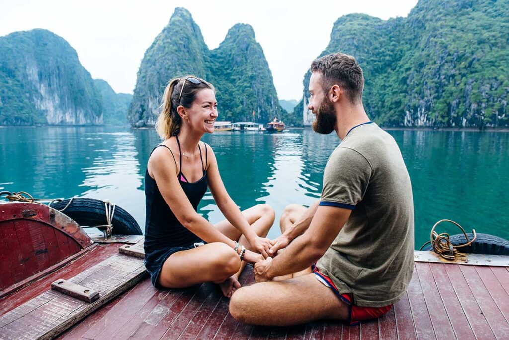 Ein Paar sitzt während seiner Flitterwochen in Vietnam an Deck eines Kreuzfahrtschiffs in der Halong-Bucht.