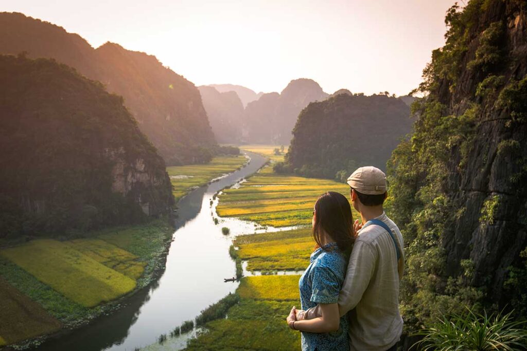 Ein Paar hält sich während seiner Flitterwochen in Vietnam fest und genießt den Blick auf die Reisfelder in Tam Coc