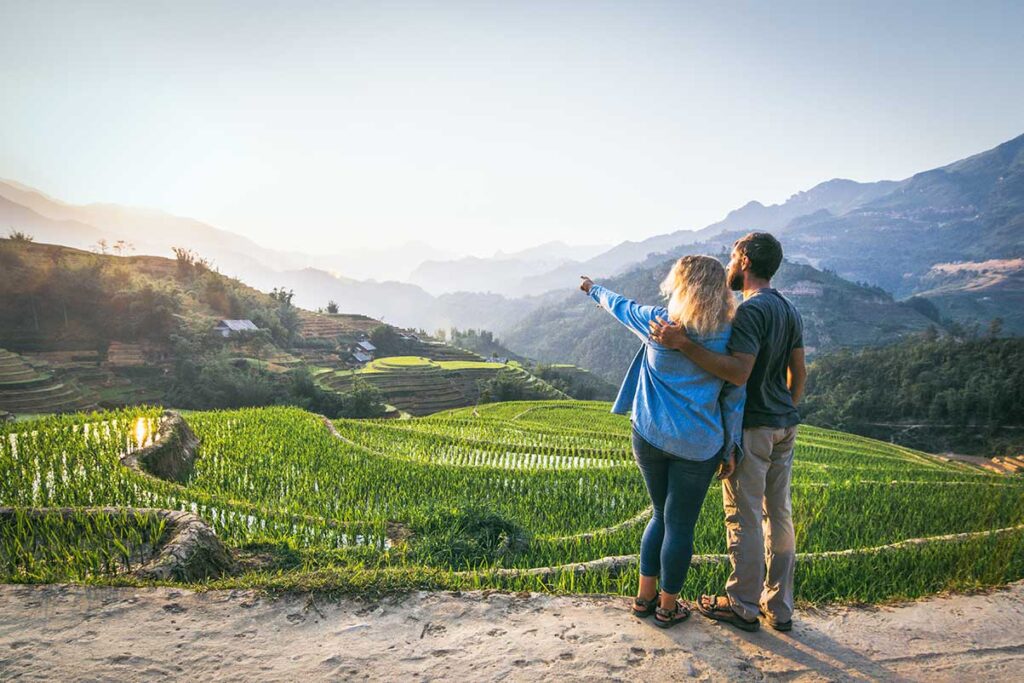 Ein Paar steht nebeneinander und ruht sich während eines Trekkings in Sapa aus, mit Blick auf die Reisterrassen während ihrer Flitterwochen durch Vietnam