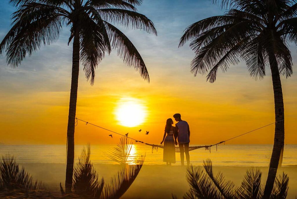 Paar an einem Strand von Phu Quoc beobachtet den Sonnenuntergang während der Flitterwochen in Vietnam