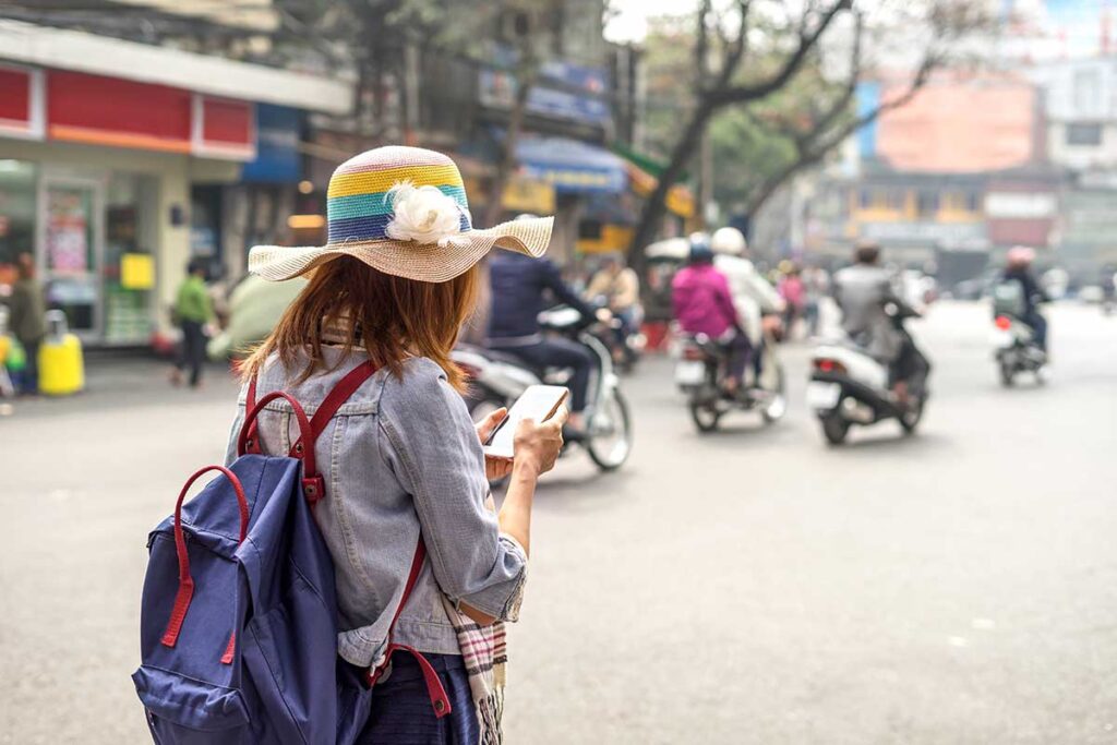 Eine junge Frau nutzt ihr Telefon mit einer lokalen vietnamesischen SIM-Karte, eine Navigations-App, um sich in Vietnam zurechtzufinden