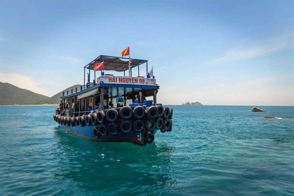 Blaues Tauchboot fährt durch das klare Wasser bei den Inseln vor Nha Trang mit sichtbarer Tauchflagge an Bord — Vietnam Active ist einer der Tauchoperatoren, der Tagesausflüge von Nha Trang aus anbietet