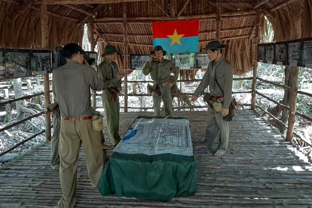 Wachsfiguren von Vietcong-Kommandeuren, die in einer Reethütte im Sac-Wald des Can Gio Reservats eine Militärkarte studieren, mit der Flagge der Nationalen Befreiungsfront an der Wand — die Guerillabasis im Sac-Wald spielte eine Schlüsselrolle während des Vietnamkriegs