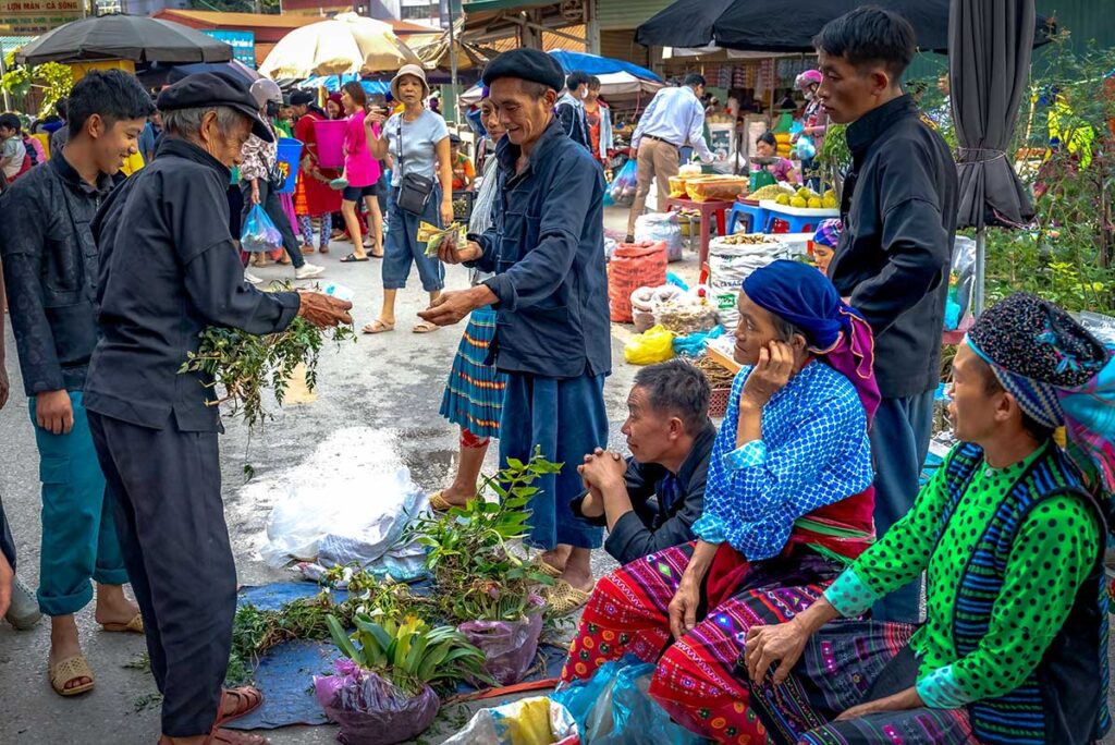 Menschen ethnischer Minderheiten in traditioneller Kleidung auf einem lokalen Markt in Ha Giang, das Respektieren lokaler Kulturen ist ein Kernelement des verantwortungsvollen Reisens in Nordvietnam