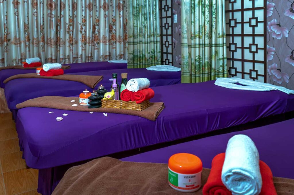 Vorbereiteter Massagesalon in Vietnam mit lila Betten, aufgerollten Handtüchern und Massageöl bereit zur Nutzung