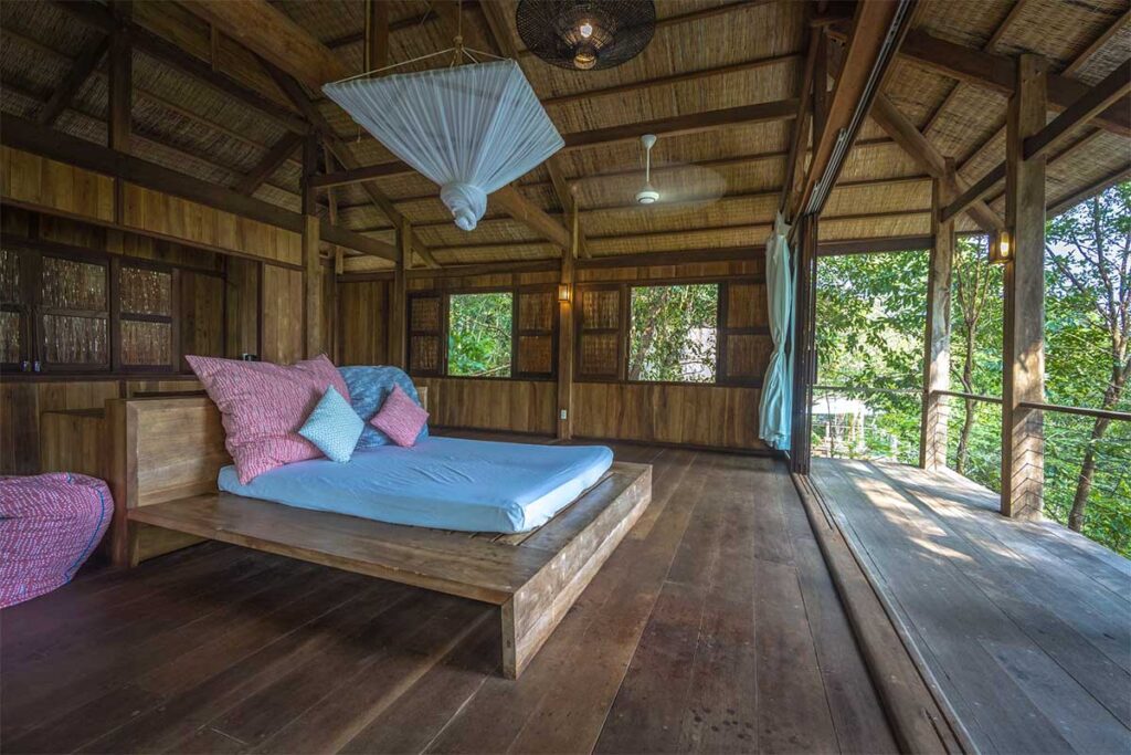 Holzbungalow auf Phu Quoc mit Moskitonetz über dem Bett und Blick auf den grünen Regenwald — ein wirksamer Schutz gegen Mücken in Vietnam