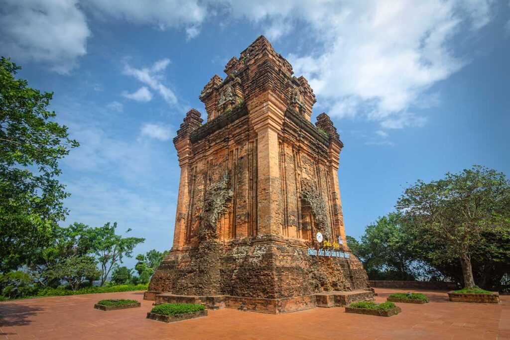 Der Nhan Tower, ein gut erhaltener Cham-Tempelturm aus dem elften Jahrhundert auf einem Hügel bei Tuy Hoa, umgeben von Bäumen und blauem Himmel — eines der wenig besuchten Cham-Denkmäler in Zentralvietnam