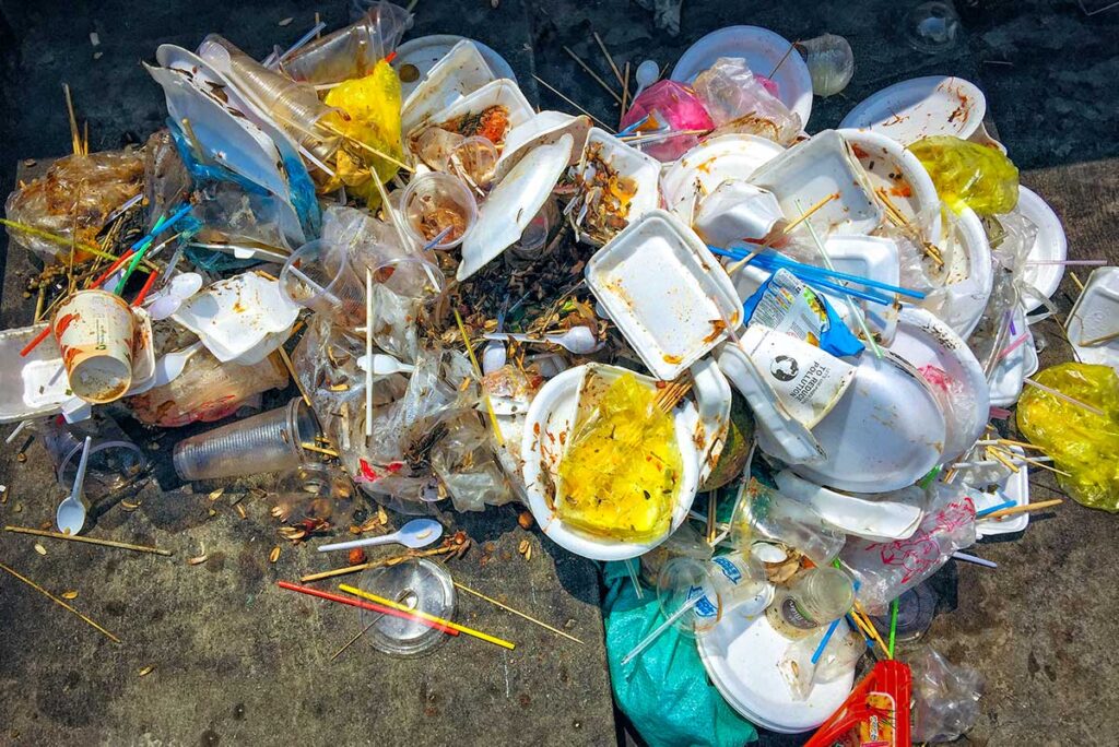 Berg aus Einwegplastikmüll auf der Straße in Vietnam, eine Erinnerung an die Plastikverschmutzung mit der nachhaltige Reisende in Vietnam bewusst umgehen
