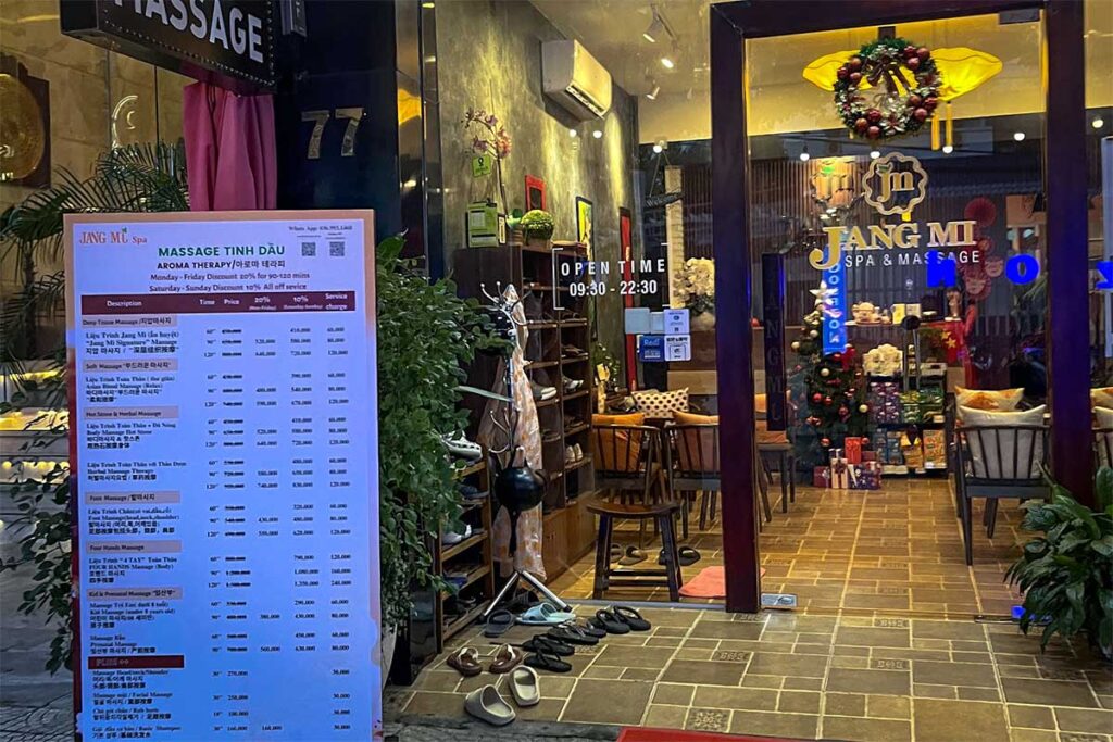 Detaillierte Preisliste mit Massagepreisen in vietnamesischem Dong außerhalb eines Massagesalons in Vietnam, mit Behandlungen wie Deep Tissue, Hot Stone und Fußmassage
