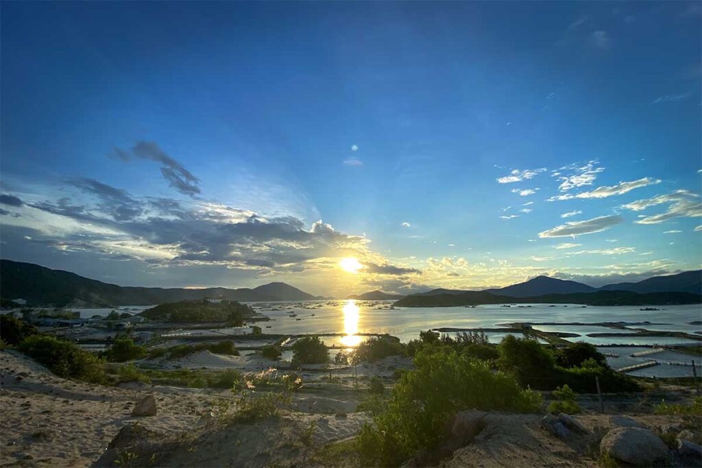 Sonnenuntergang über der Van Phong Bay von der Dam Mon Halbinsel aus gesehen, mit Fischzuchtanlagen im Wasser, Inseln und Bergen in der Ferne — een ruhiger und wenig besuchter Aussichtspunkt
