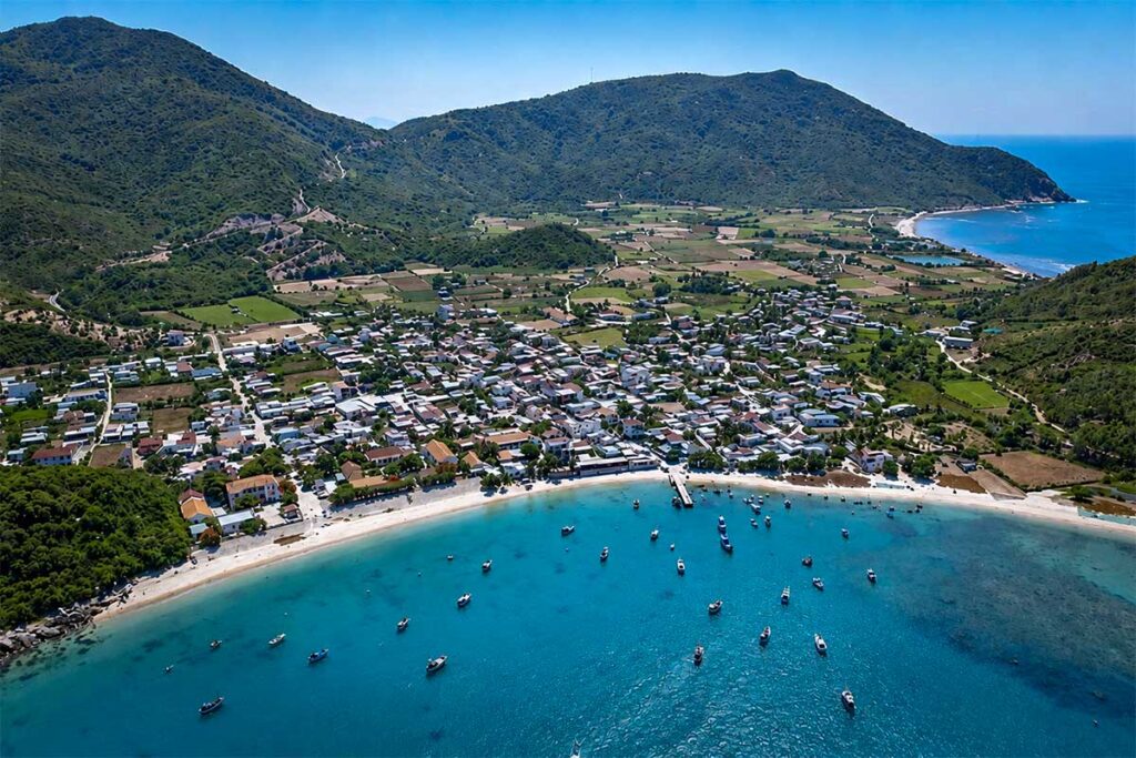 Luftaufnahme des Fischerdorfs an der Küste der Ninh Van Bay mit weißen Häusern, Fischerbooten im türkisfarbenen Wasser und grünen Bergen im Hintergrund — das Dorf ist nur per Boot erreichbar