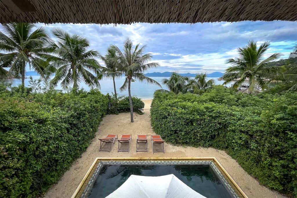 Blick aus einer Villa des Six Senses Ninh Van Bay über einen Privatpool, Liegestühle, Palmen und die ruhige Bucht im Hintergrund — eines der exklusivsten Resorts bei Nha Trang