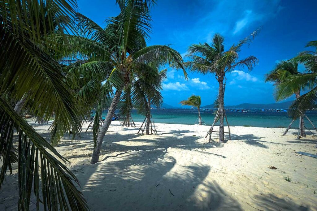 Weißer Sandstrand in Son Dung in der Van Phong Bay mit Palmen und blauem Himmel — ein ruhiger und wenig besuchter Strand am Rand der Bucht